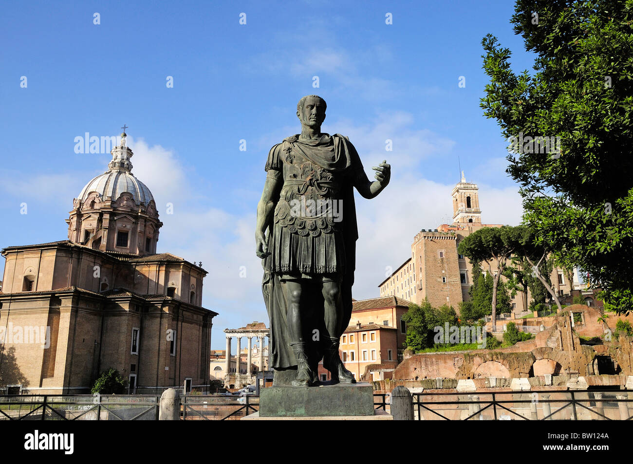Bronze statue of Julius Caesar with Foro Romano behind, Fori Imperiali Stock Photo