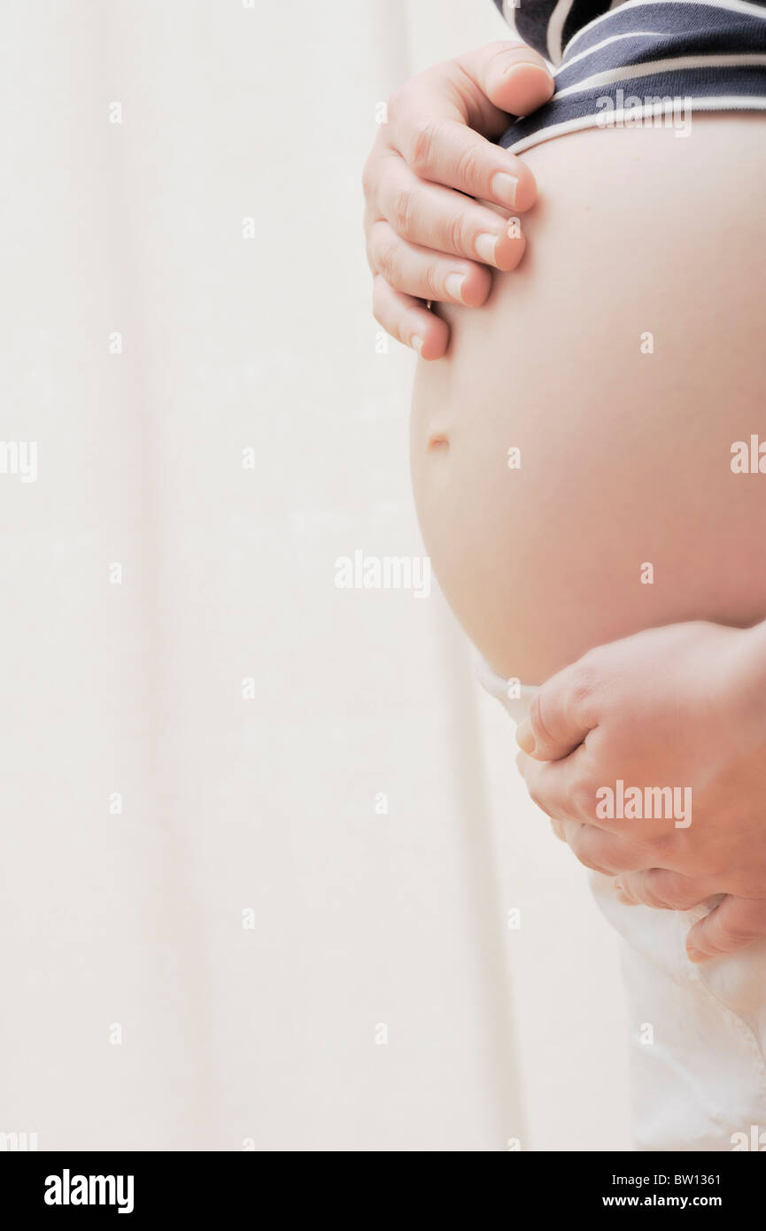 Pregnant woman holding hands on her belly Stock Photo