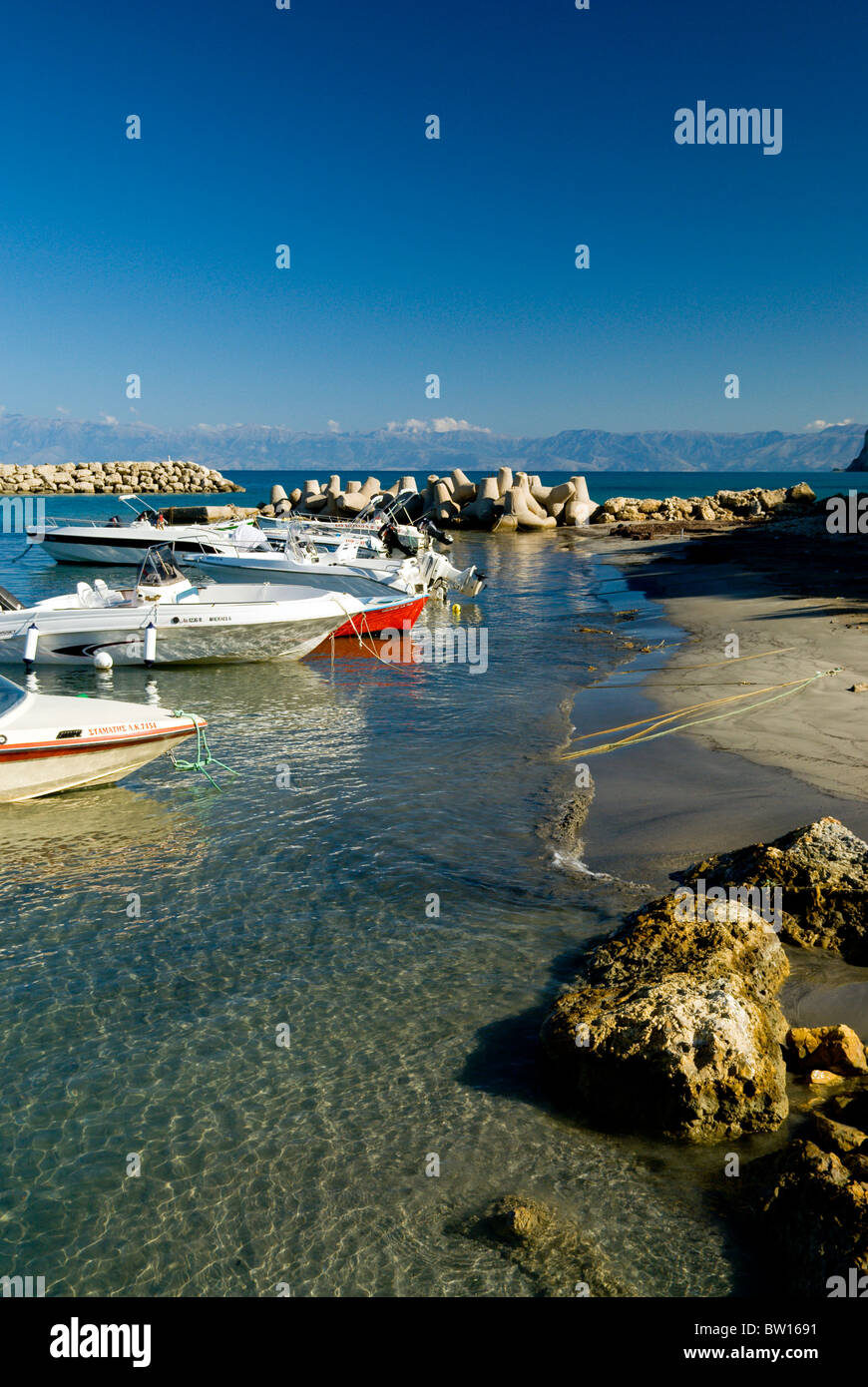 boats moored in new harbour, with the mountains of albania in the distance, san stefanos, north west, corfu, ionian islands, gre Stock Photo