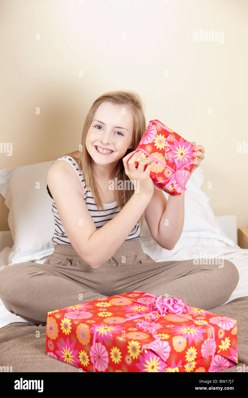 A teenage girl opens birthday presents in her bedroom UK Stock Photo
