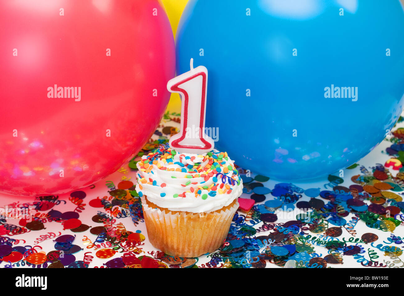Celebration with balloons, confetti, cupcake, and number 1 candle. Stock Photo