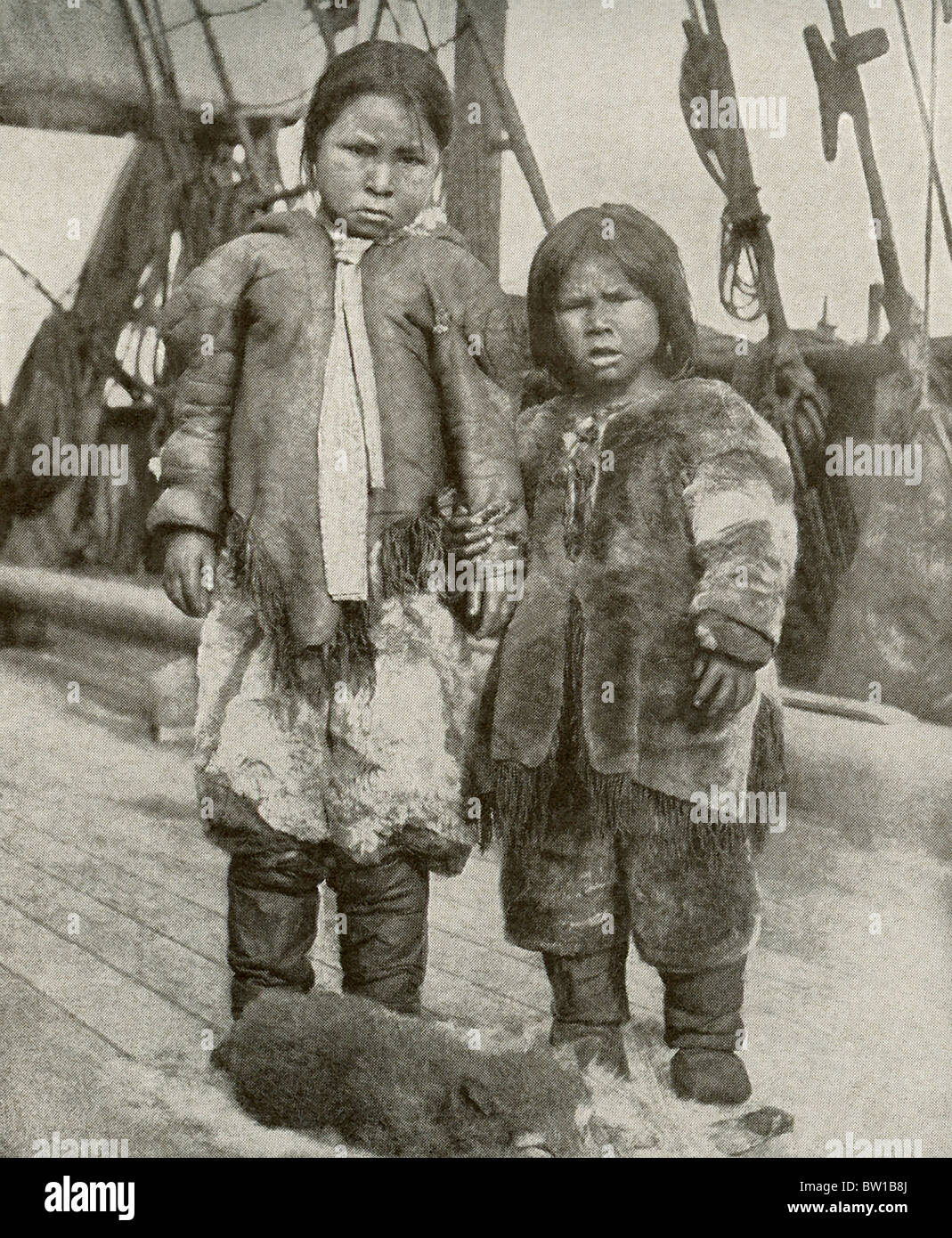 Two young Eskimo children pose for a photo aboard a vessel whose crew was hunting polar bears. Stock Photo