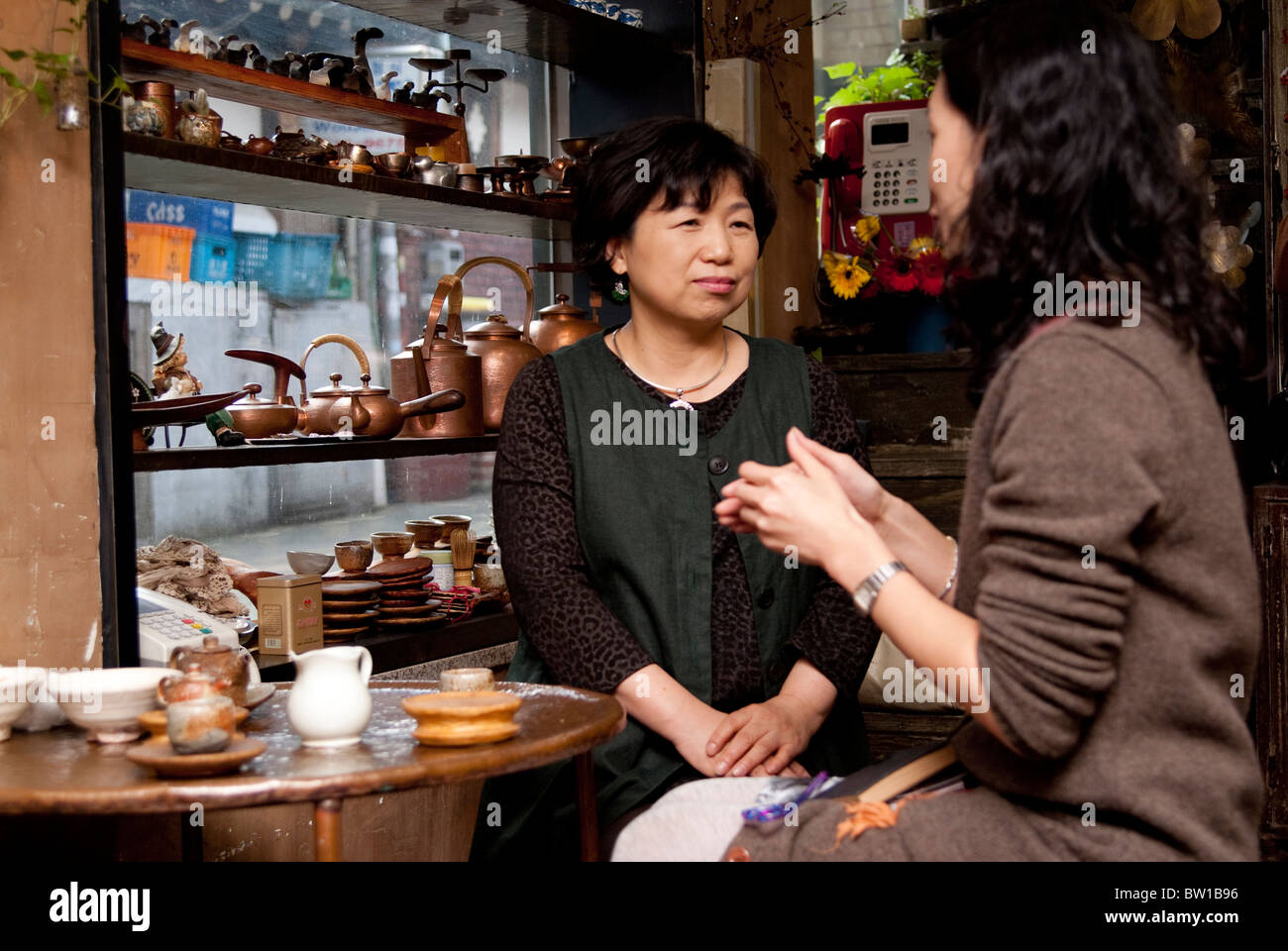 A Korean jewelry and accessory shop owner talking and having tea with a guest, Insadong, Seoul, South Korea Stock Photo