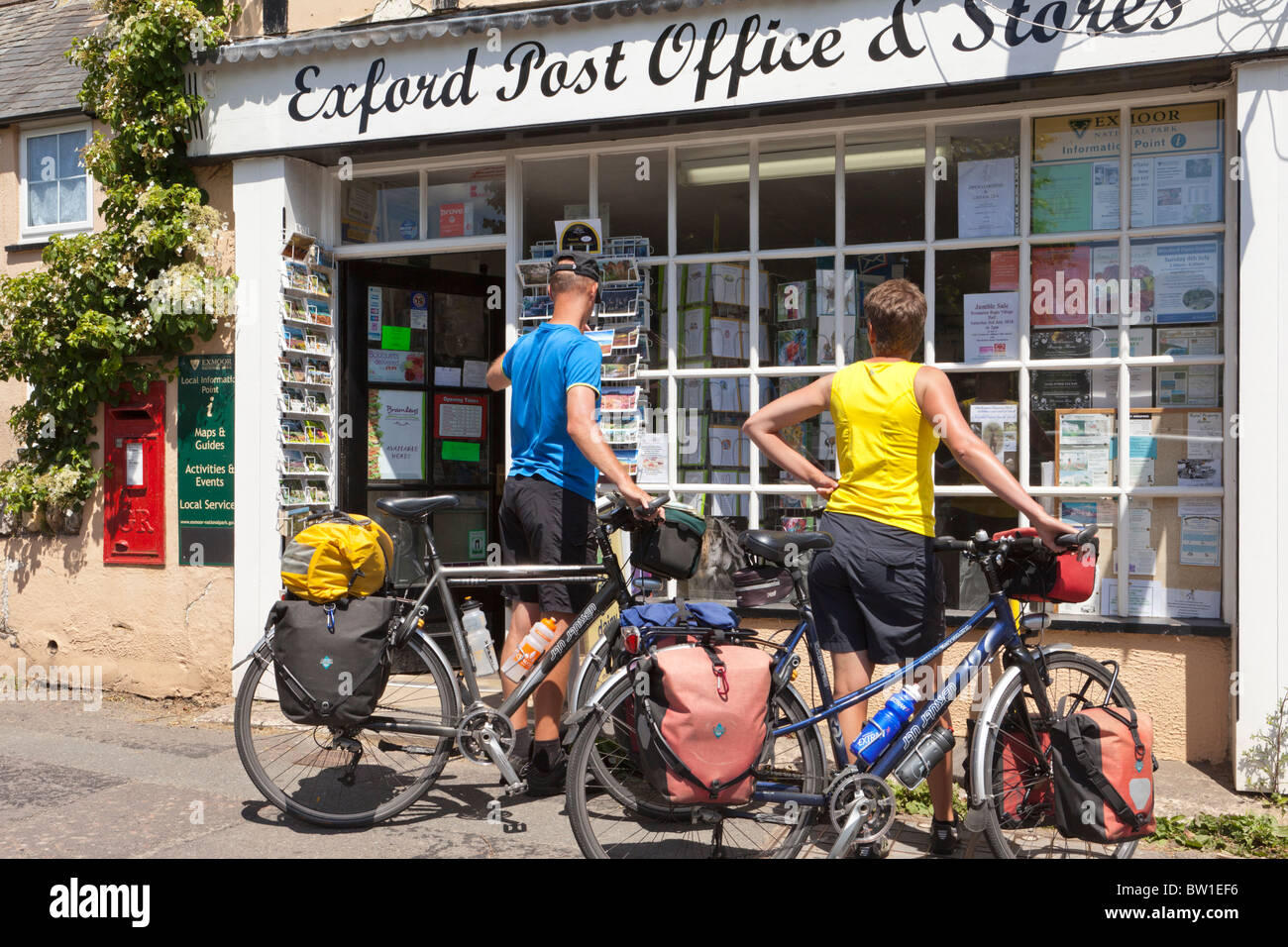 A couple of touring cyclists looking at postcards in the Exford Post Office & Stores in the Exmoor village of Exford, Somerset UK Stock Photo