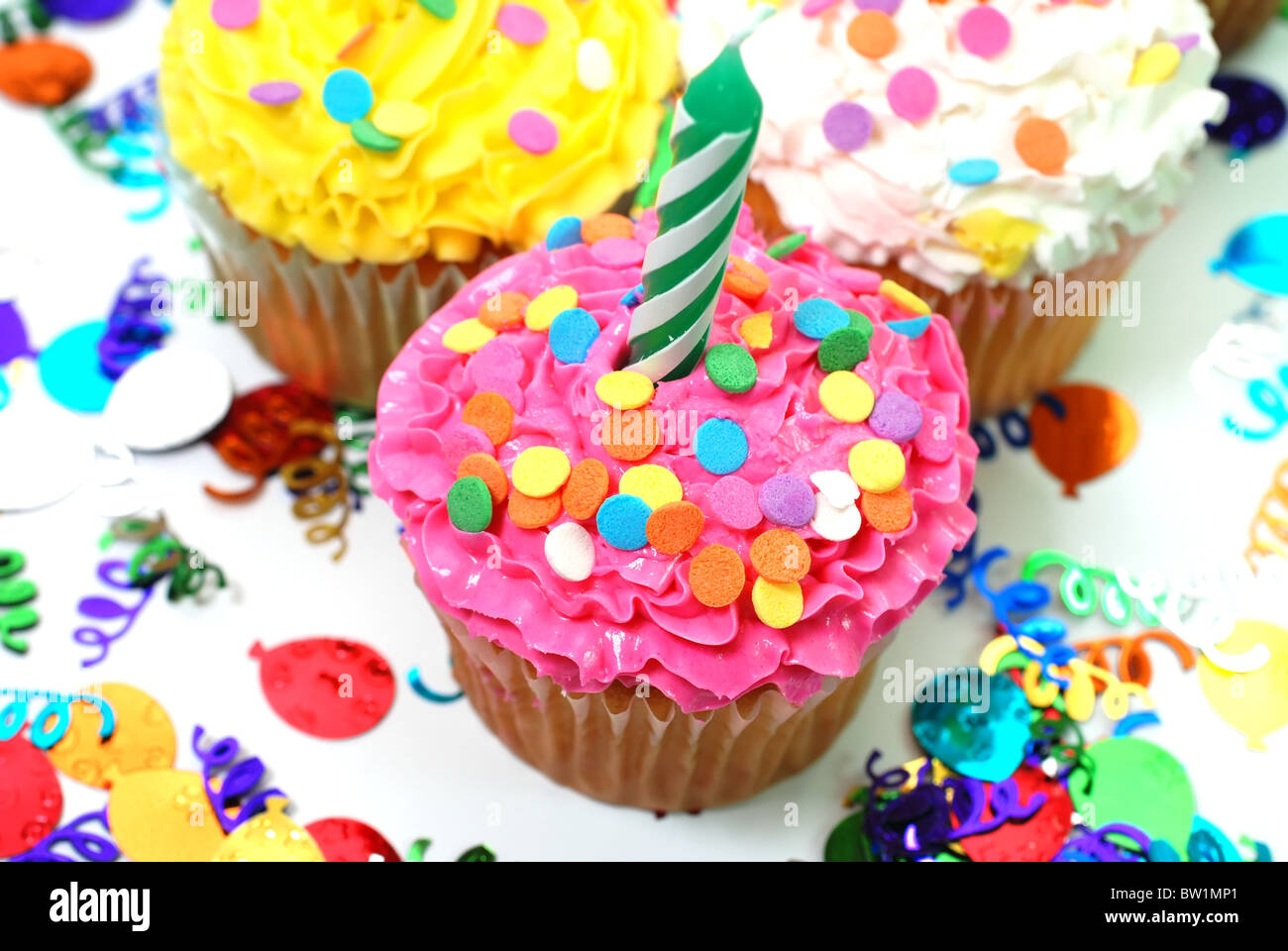 Celebration cupcakes with candles and sprinkles. Confetti in background ...