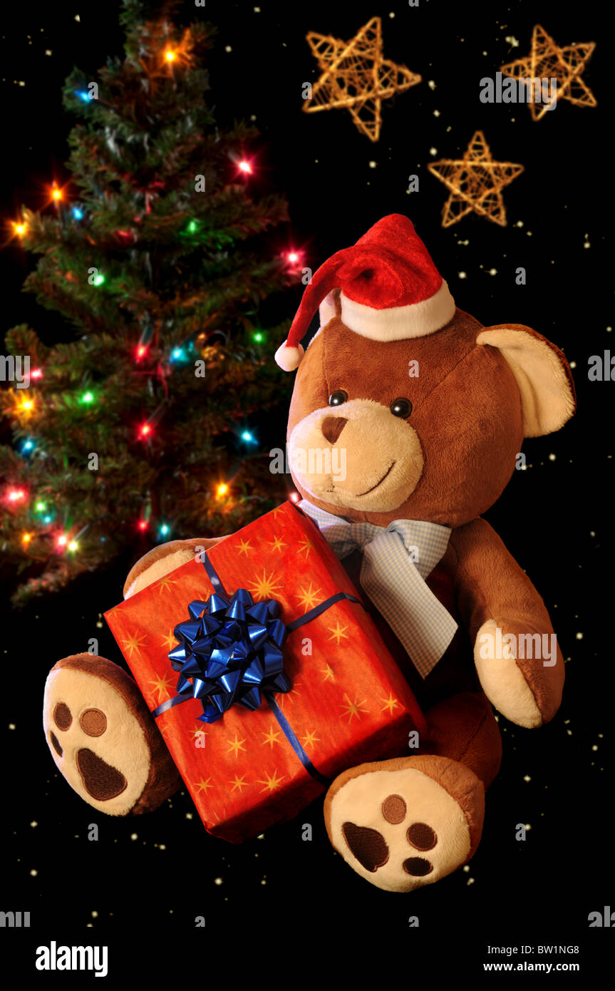 Christmas teddy bear with gift and decorated tree. Stock Photo