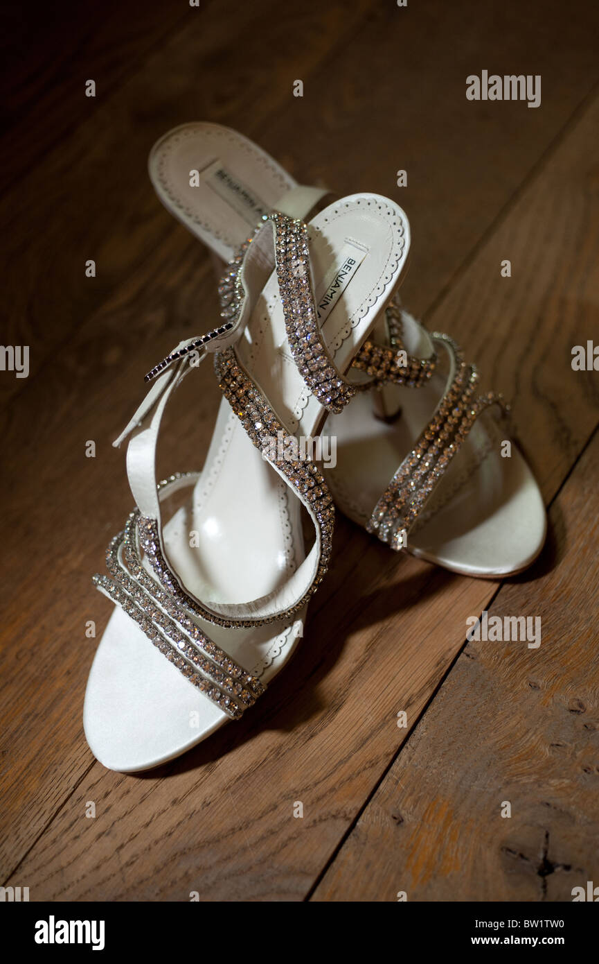 A pair of Ladies white diamanté Wedding Shoes in a pool of light on an oak floor Stock Photo