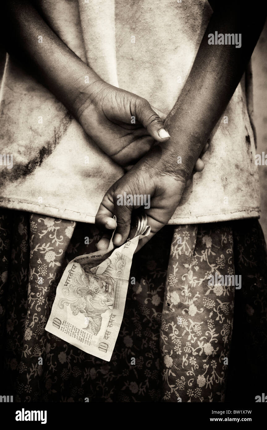 Indian street girl begging for money, holding it behind her back. Andhra Pradesh, India. Sepia toned. Stock Photo