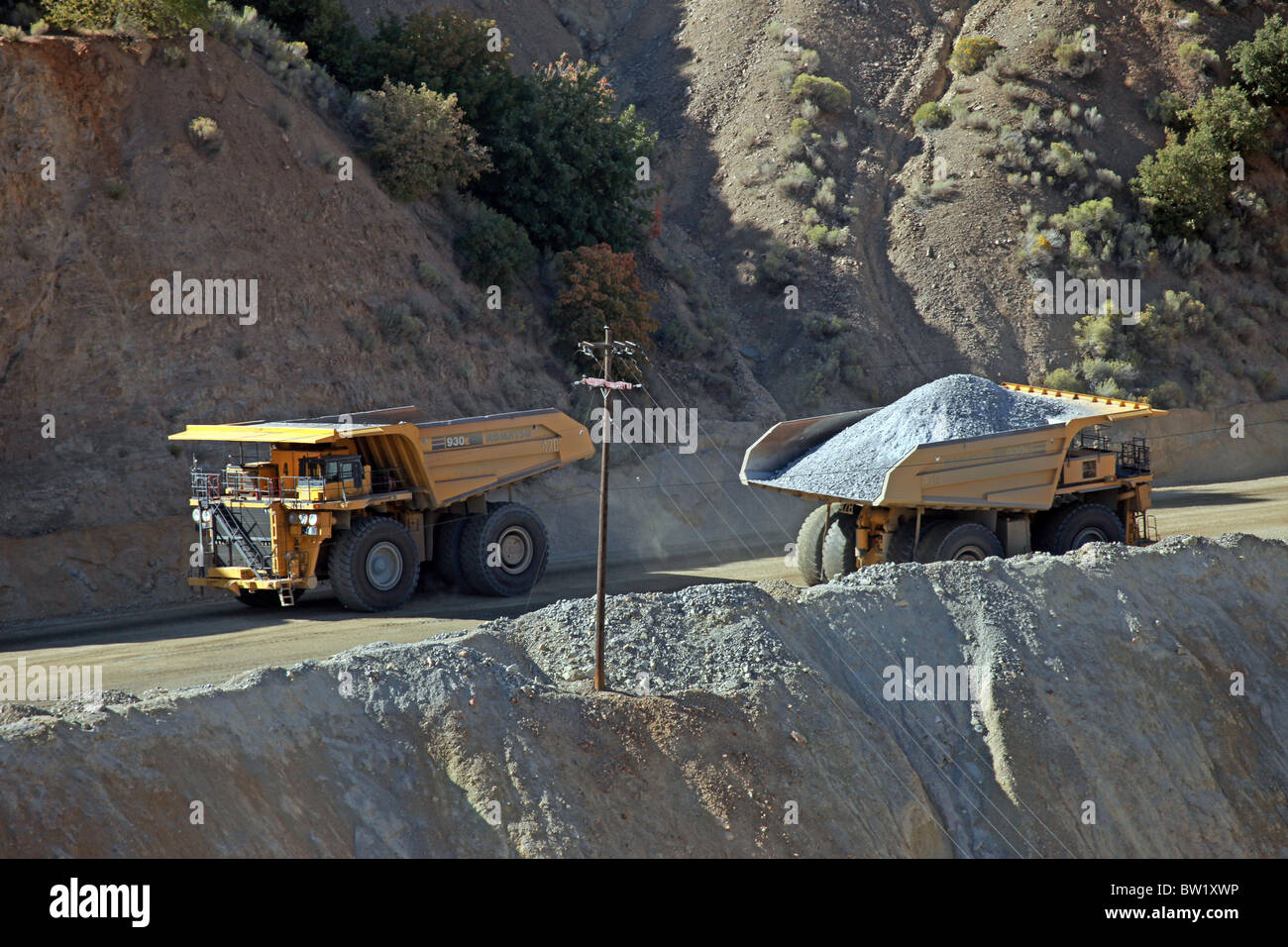 Large mine trucks moving loads of ore on road. Kennecott Copper Mine. Heavy industrial work. Stock Photo