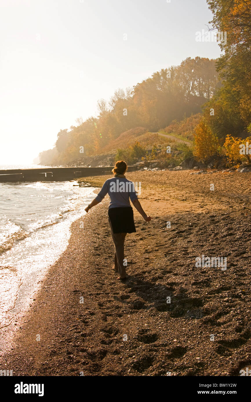 A woman walks alone on a beach in autumn. Stock Photo