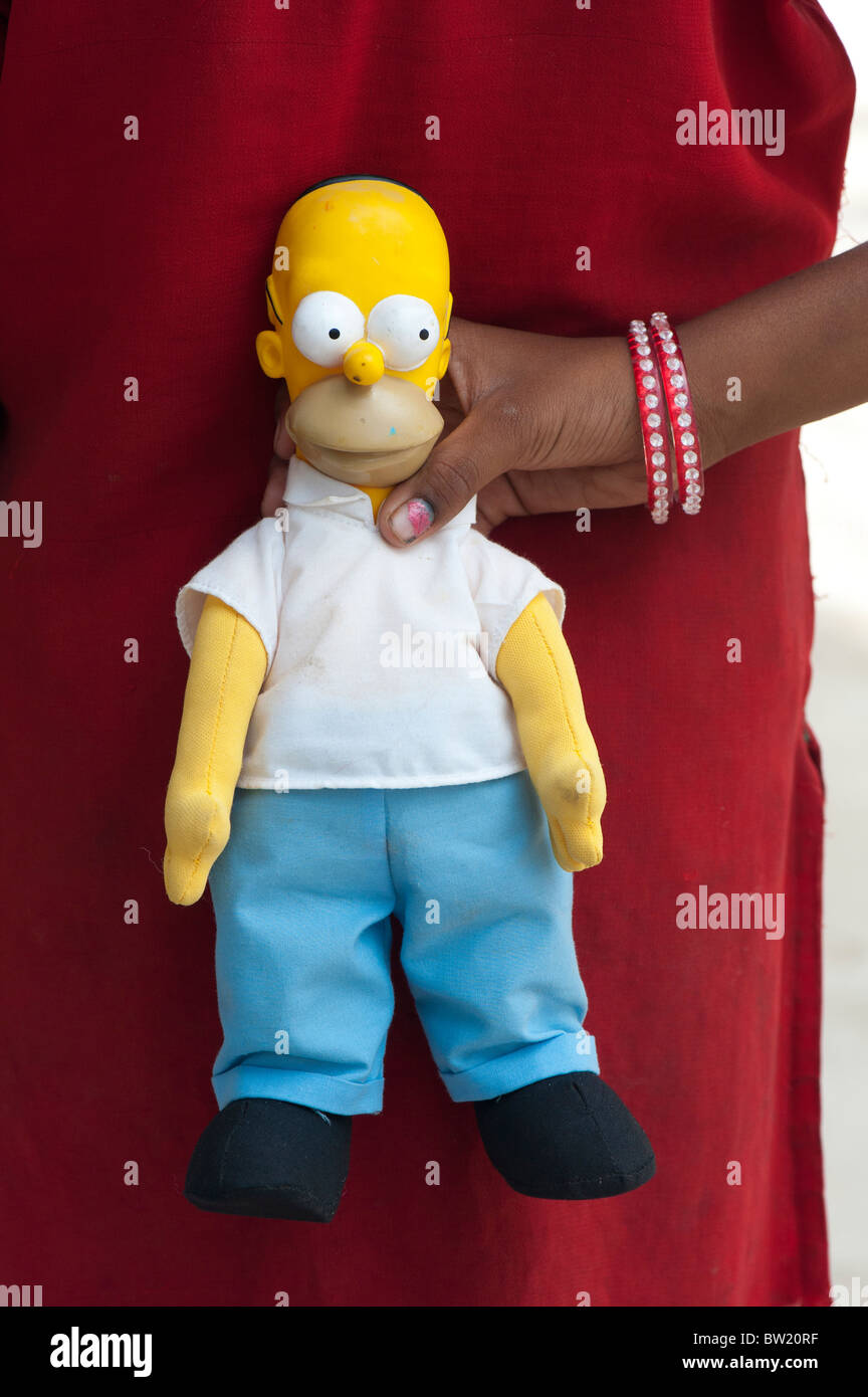 Young Indian street girl holding a homer simpson doll behind her back. Andhra Pradesh, India Stock Photo