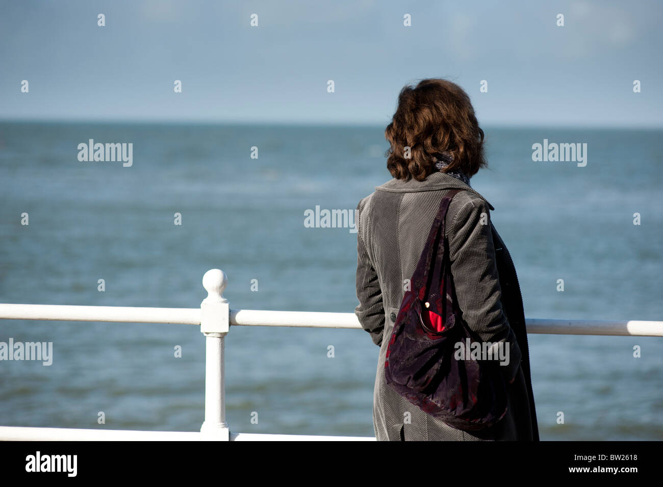 Rear view of a single woman looking out at the sea, UK Stock Photo