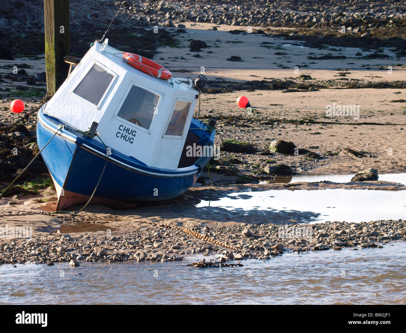 Small fishing boat beached at low tide, Bude, Cornwall, UK Stock Photo