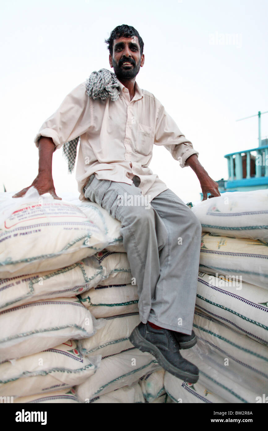 A man sitting on stacked sacks at the port, Dubai, United Arab Emirates Stock Photo