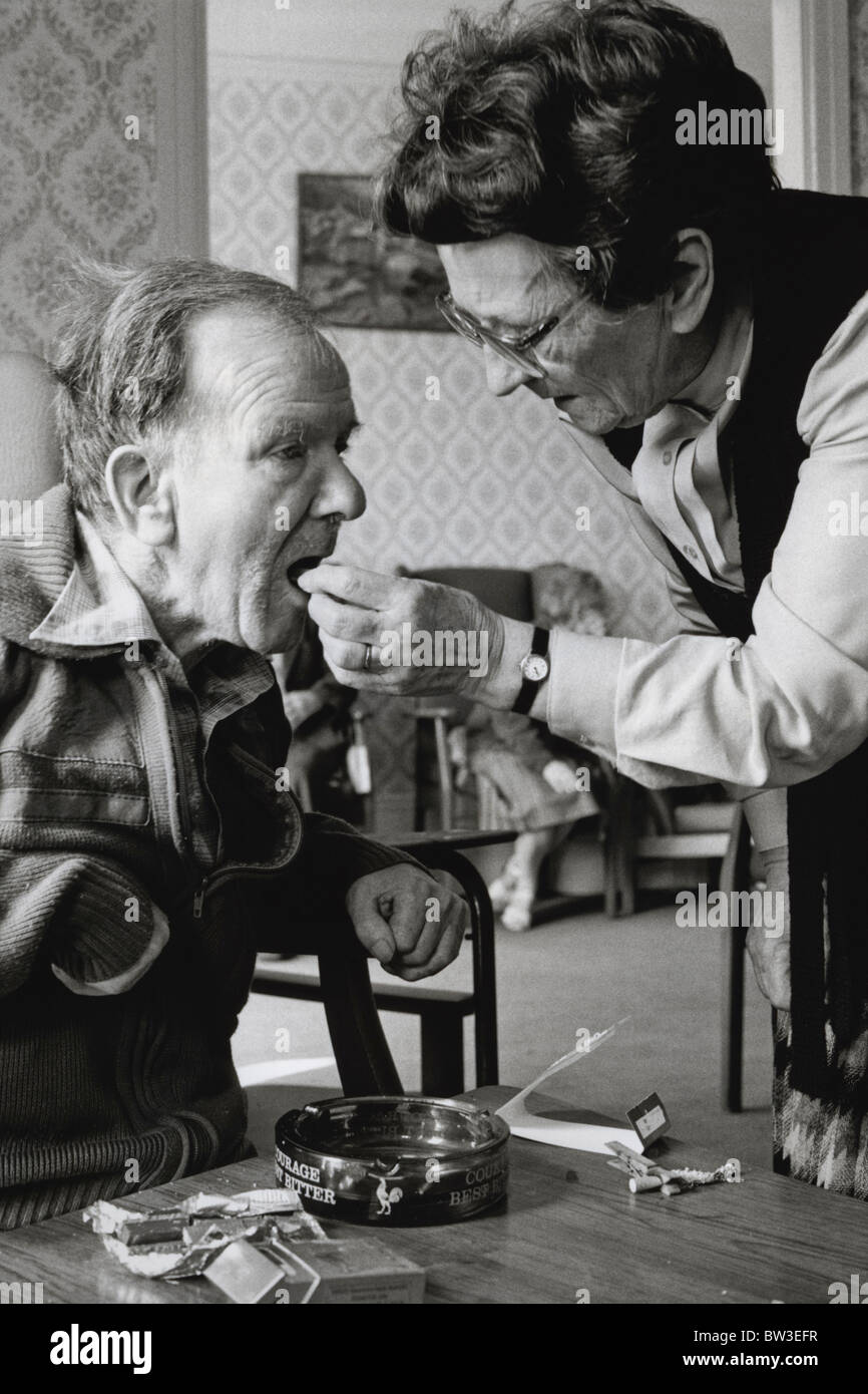WRVS lady giving elderly man chocolate at a residential care home Stock Photo