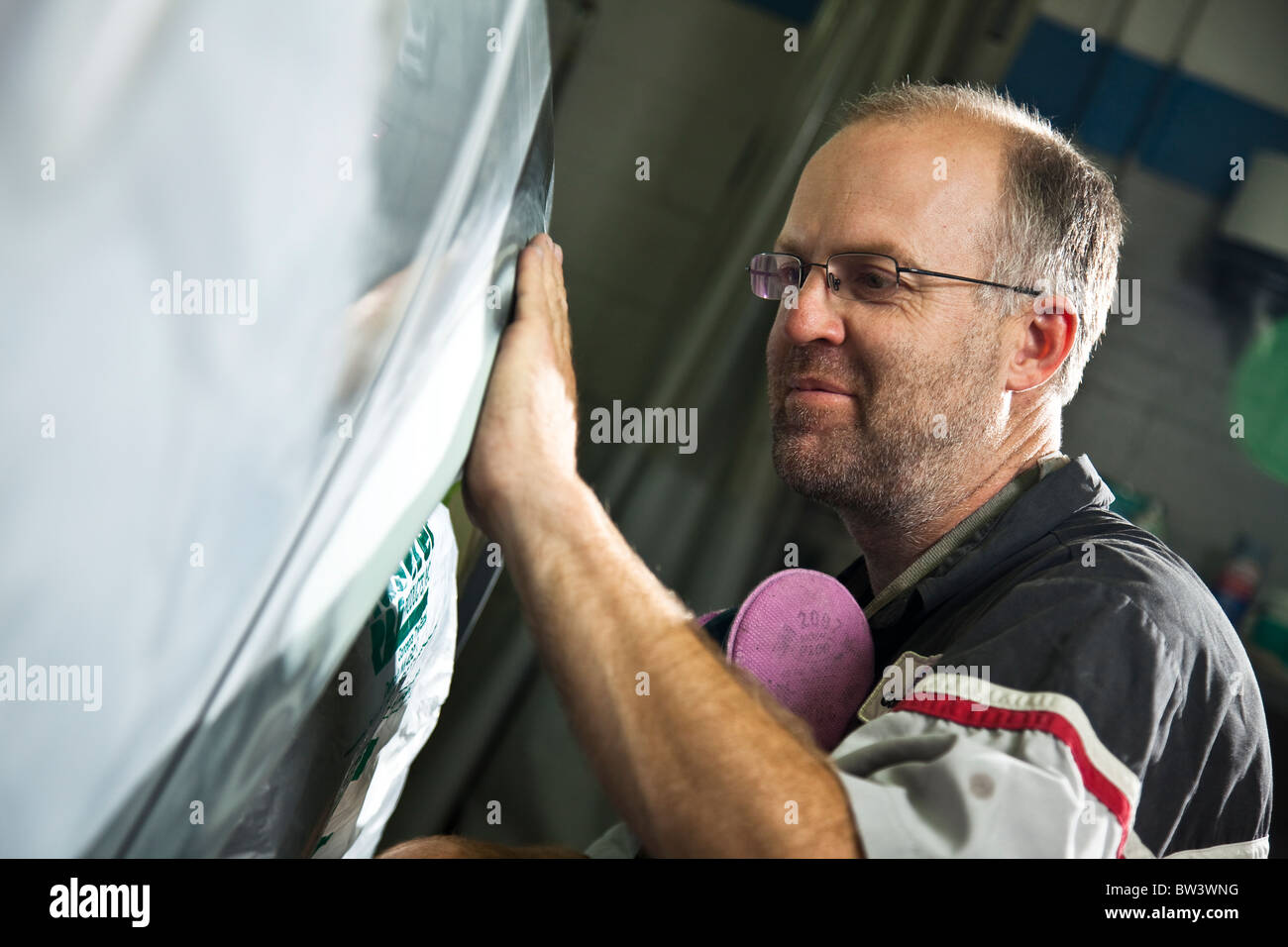 Sanding with fine sandpaper, mechanic doing body work on auto Stock