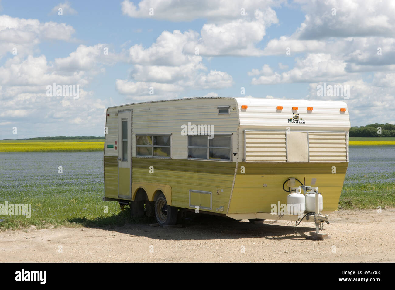 Camper trailer parked at side of alfalfa and canola field near Winnipeg, Manitoba, Canada Stock Photo