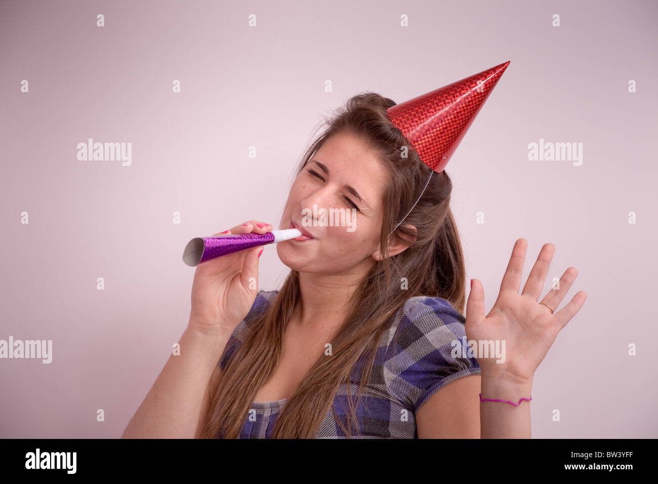 Teen girl (15 years old) with a party hat and noisemaker Stock Photo