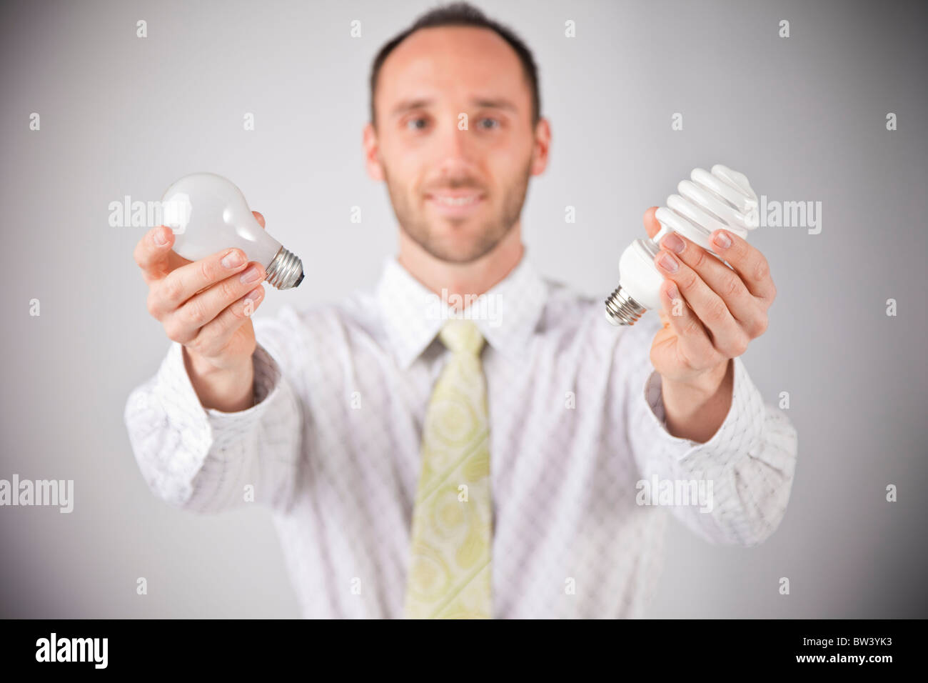 Business man holding out two light bulbs, selective focus Stock Photo