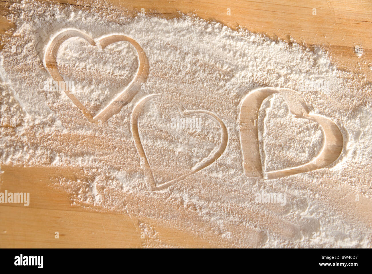 Hearts drawn in flour on wooden table top Stock Photo