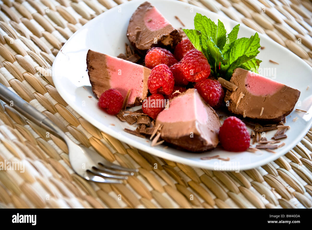 Chocolate Raspberry dessert, white plate and woven background Stock Photo