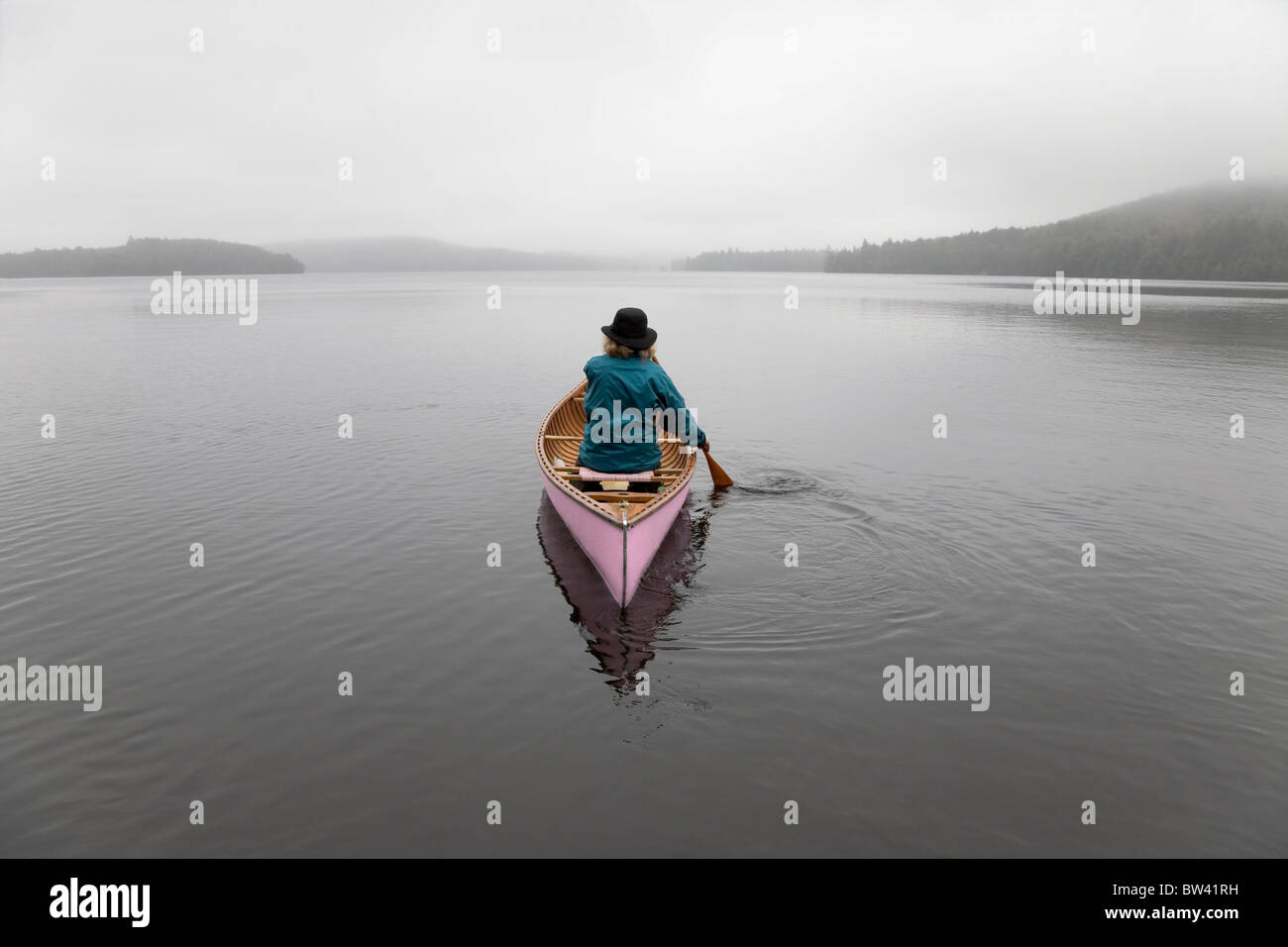 Senior woman canoeing solo on a misty morning, Algonquin Park, Ontario Stock Photo