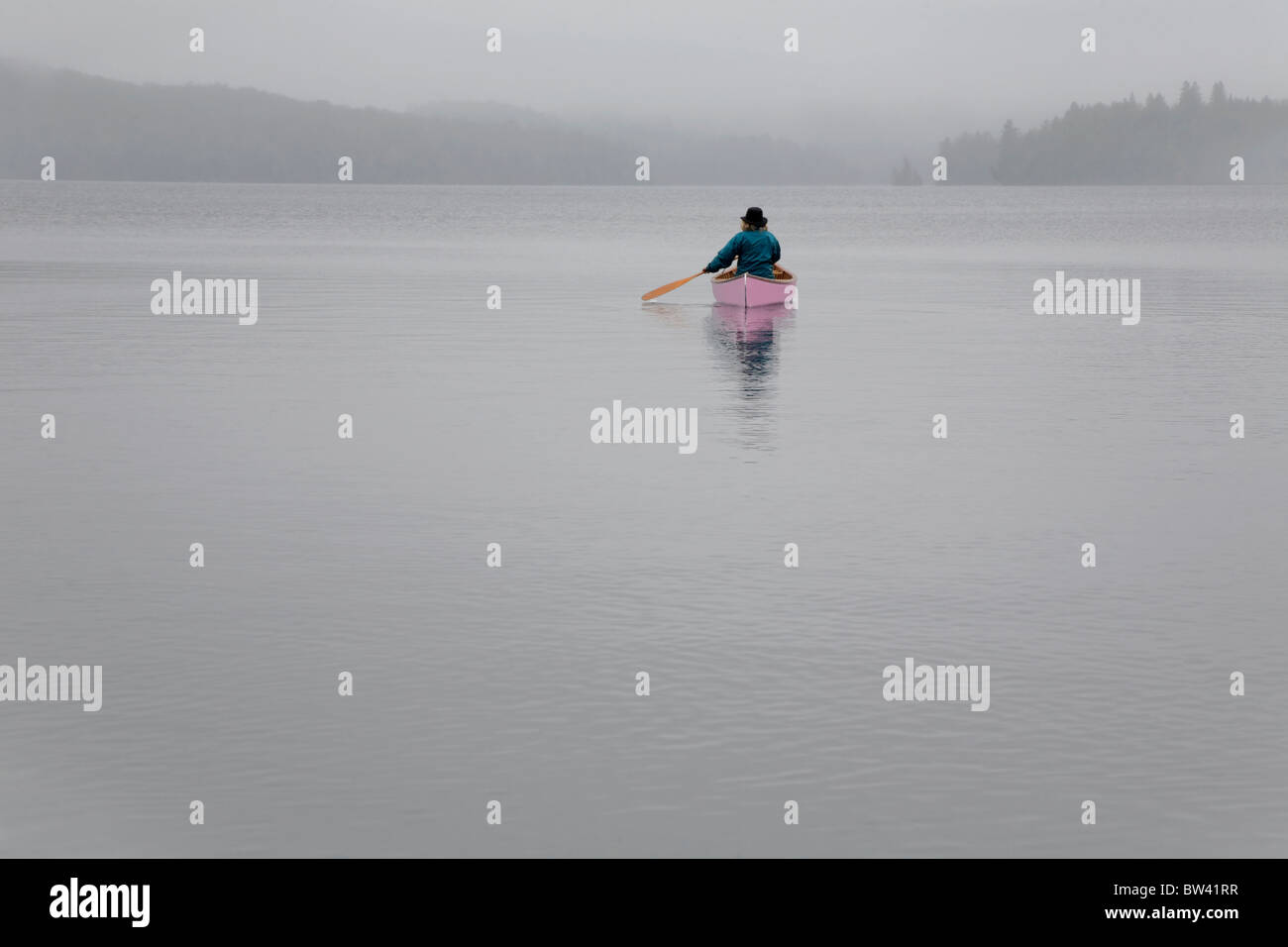 Senior woman canoeing solo on a misty morning, Algonquin Park, Ontario Stock Photo