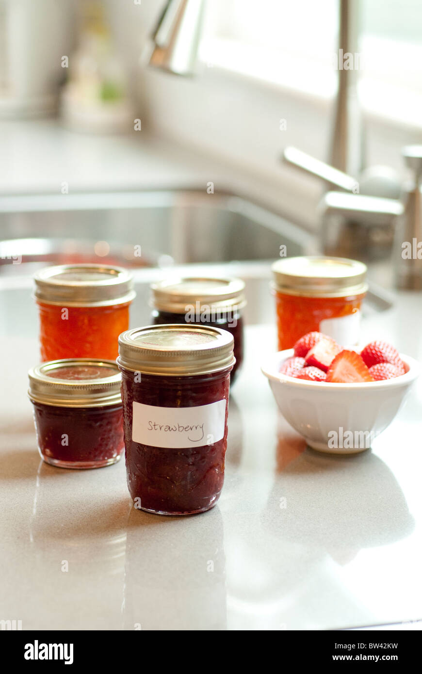 Jars of jam and strawberries on kitchen counter with kitchen sink