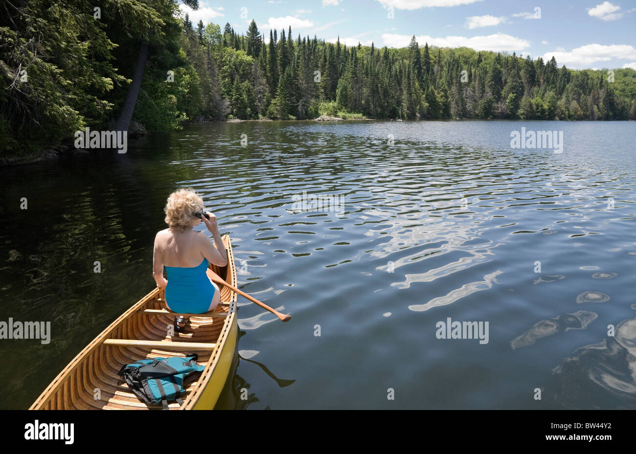 Senior woman talking on her cell phone while canoeing, Algonquin Park, Ontario Stock Photo