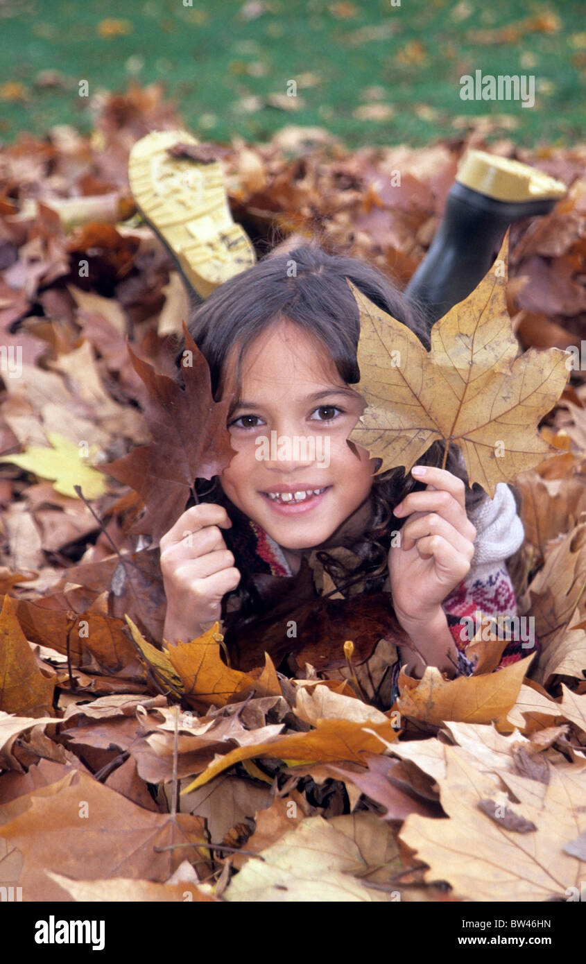 A little girl lying on a pile of Autumn leaves Stock Photo - Alamy