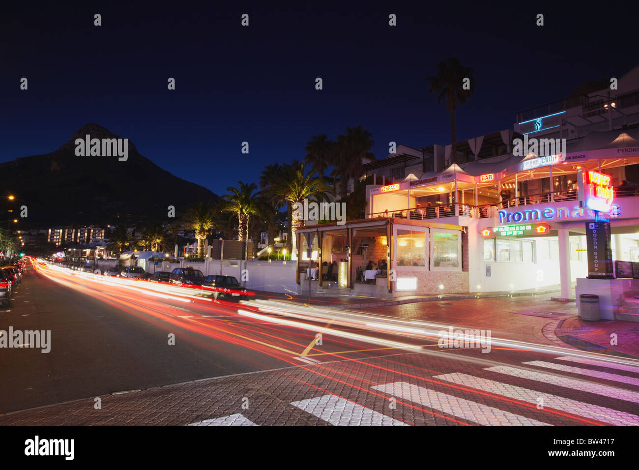 Traffic light trails passing restaurants on Victoria Road, Camps Bay, Cape Town, Western Cape, South Africa Stock Photo