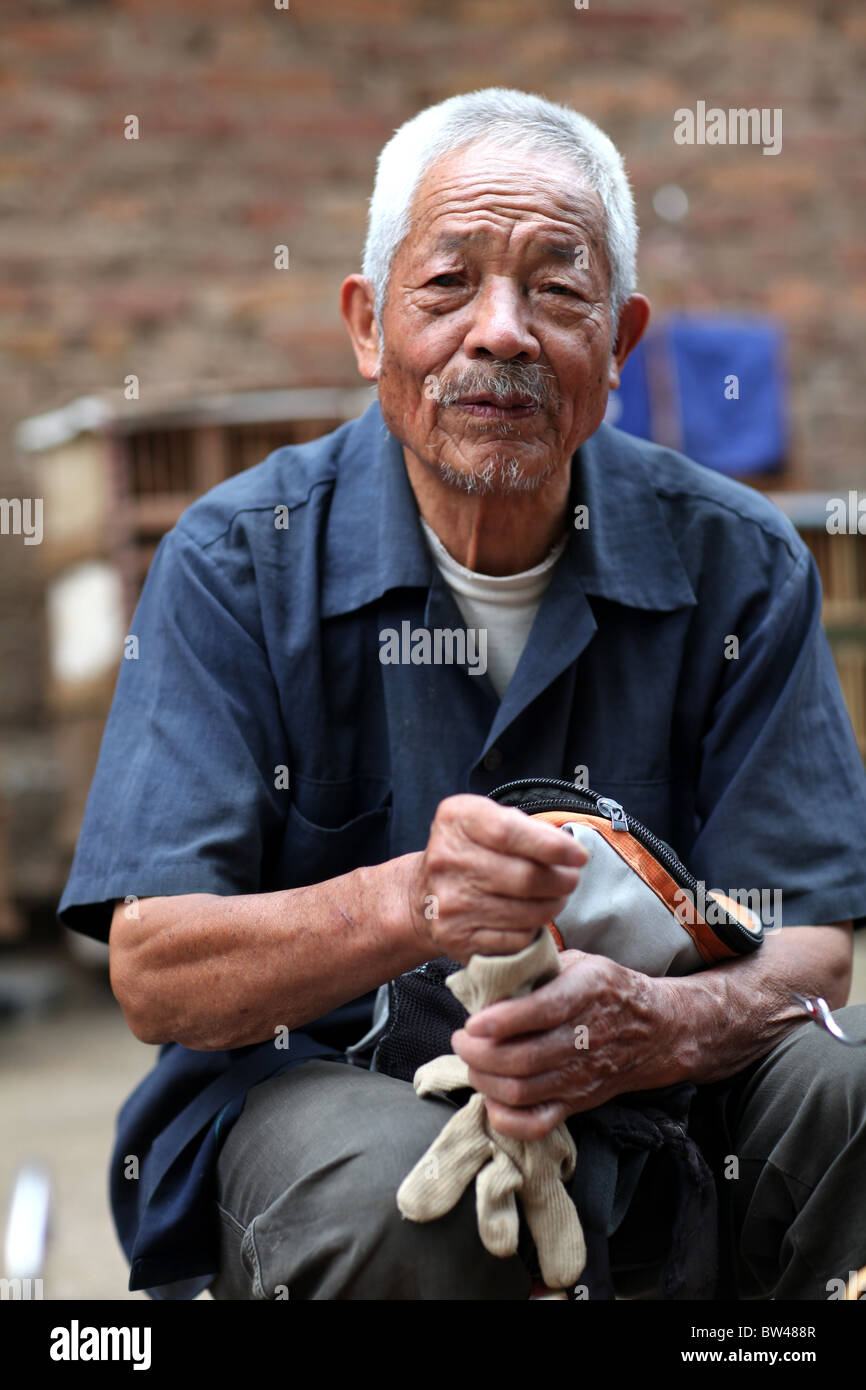 A local man selling small birds for pets, also considered lucky, on the streets in Kunming, China. Stock Photo