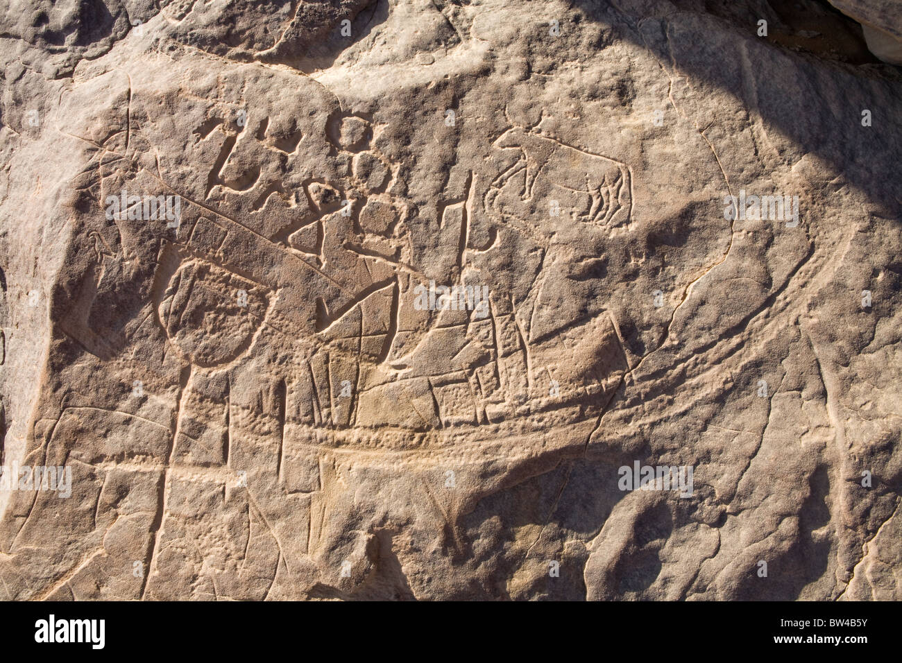 High prowed boat  with Horus on the prow and bovid attached etched on rock-face in Wadi Mineh, Eastern Desert of Egypt Stock Photo