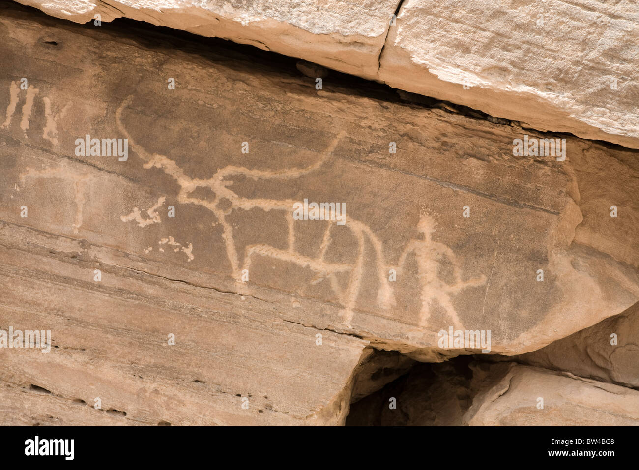 Petroglyph of man with stick holding tail of bull with large horns, Eastern Desert Egypt Stock Photo