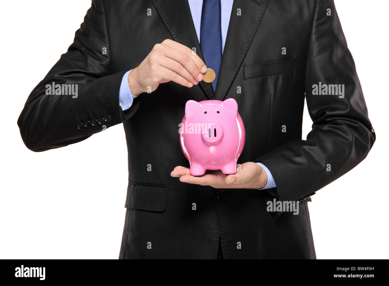 Close up of a man inserting a coin into a piggy bank Stock Photo - Alamy