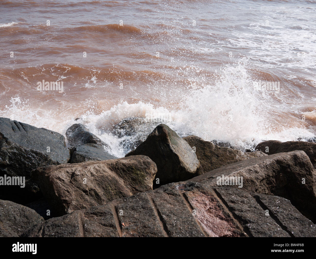 The sea breaks over large rocks which act as a breakwater in Sidmouth, Devon Stock Photo
