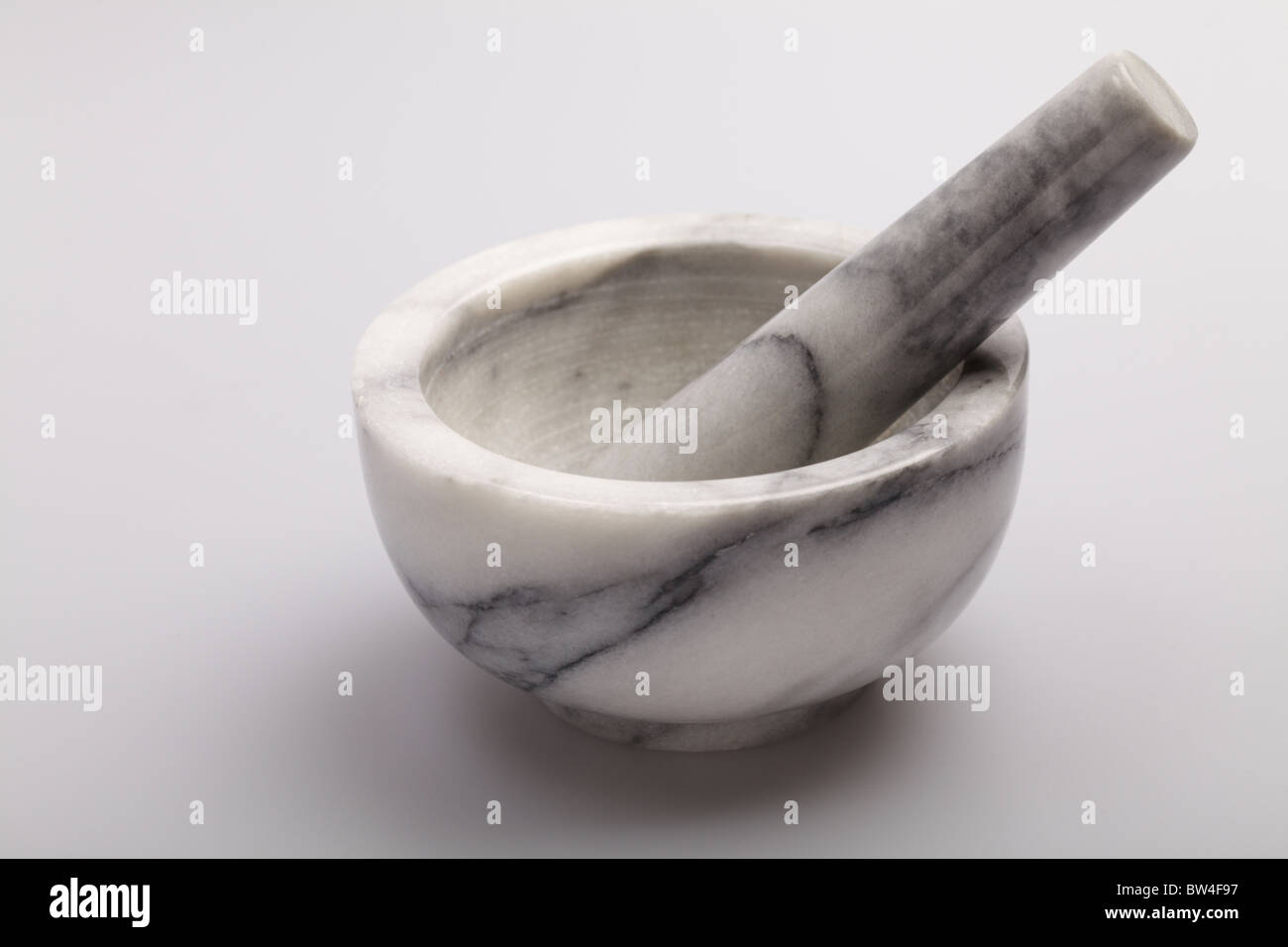 Grey and white marble pestle and mortar on a white surface Stock Photo