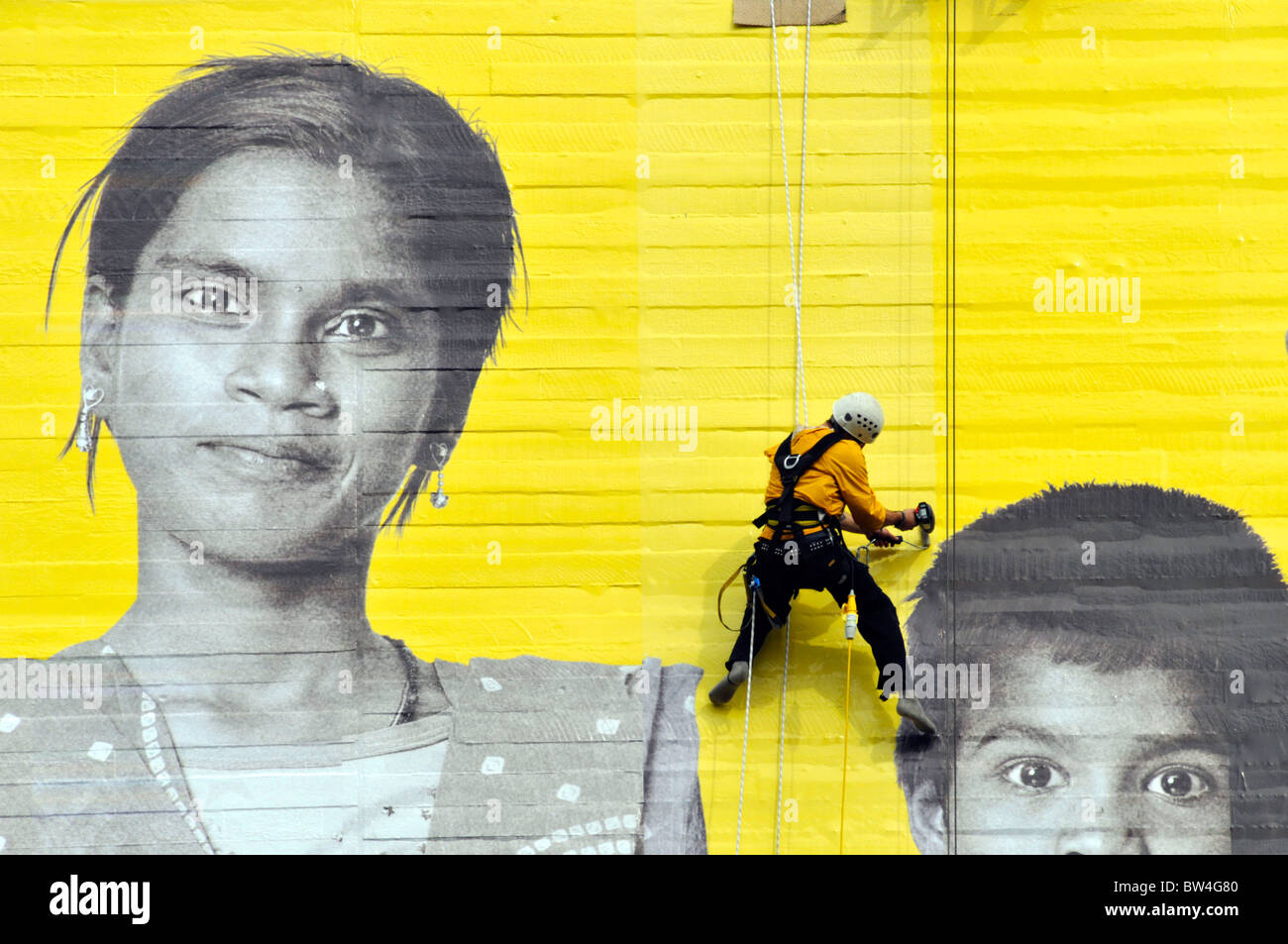 Workman fixing giant photo poster to the National Theatre as part of Aviva 'You Are The Big Picture' global advertising campaign Stock Photo