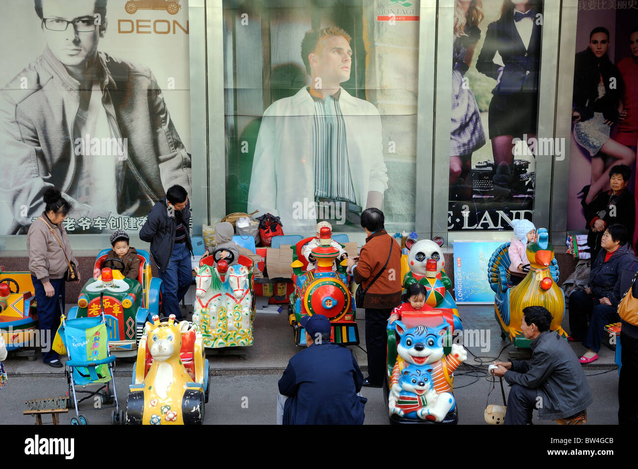Chinese children play in front of billboards featuring western fashion in Qingdao, Shandong, China.12-Nov-2010 Stock Photo