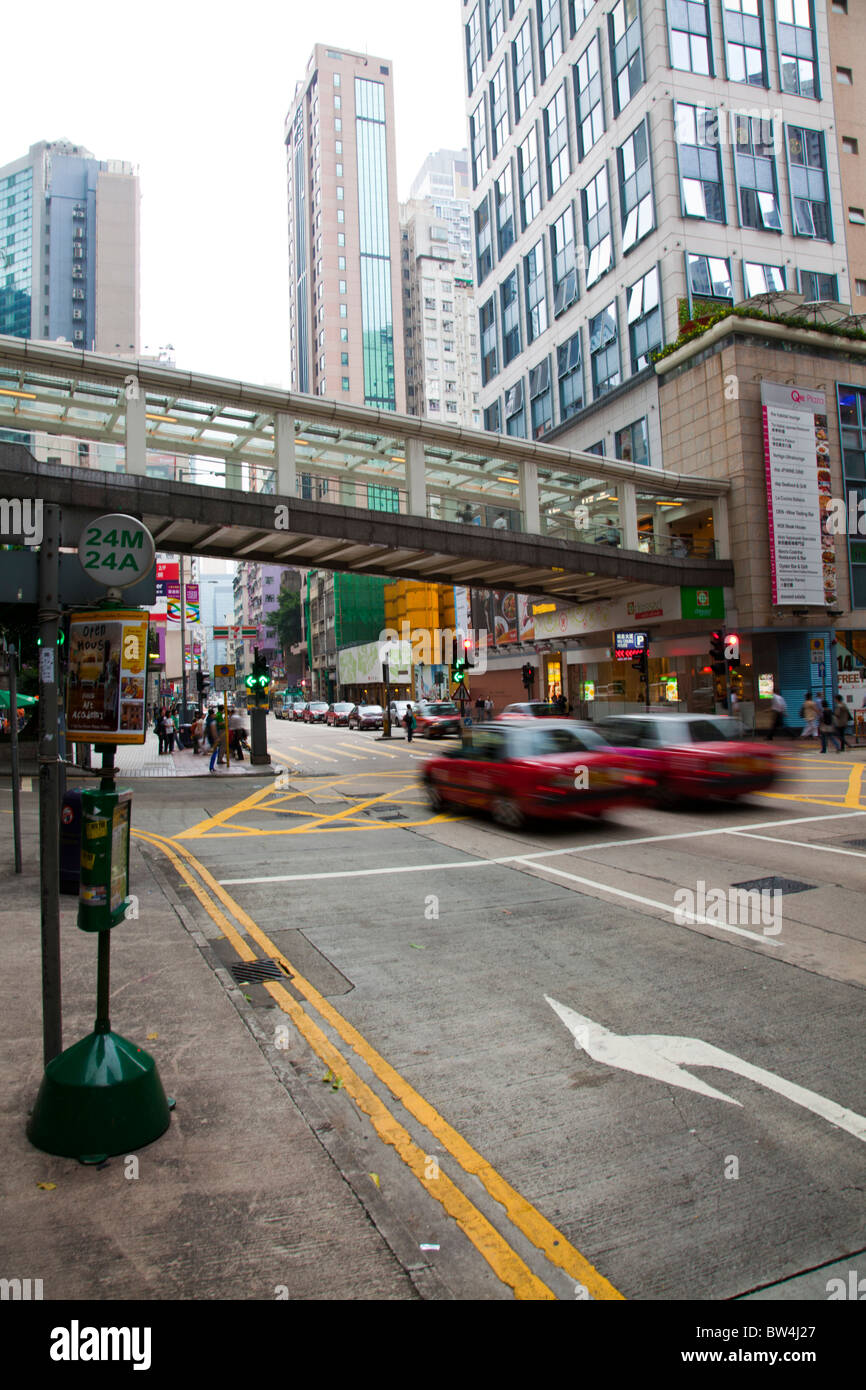 Not far from central Hong Kong, the Wan Chai neighborhood with cars speeding under overhead walkway Stock Photo