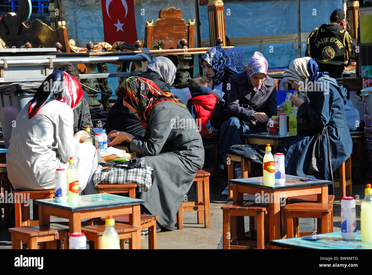 ISTANBUL, TURKEY. Young Turkish women eating balik ekmek (fish sandwiches) by the Golden Horn in Eminonu district. Stock Photo