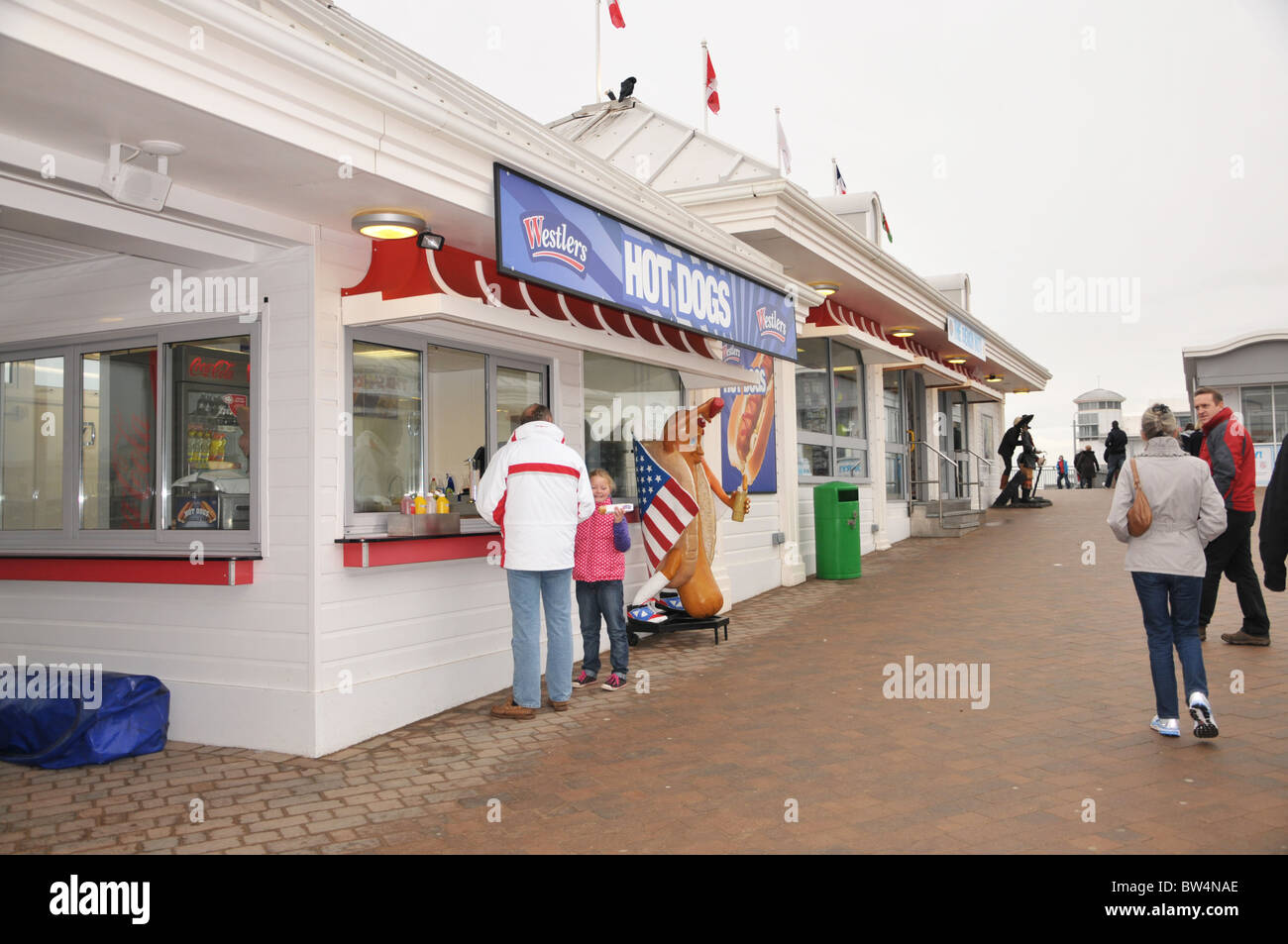 father and daughter buying a hot dog from one of the food kiosk on the