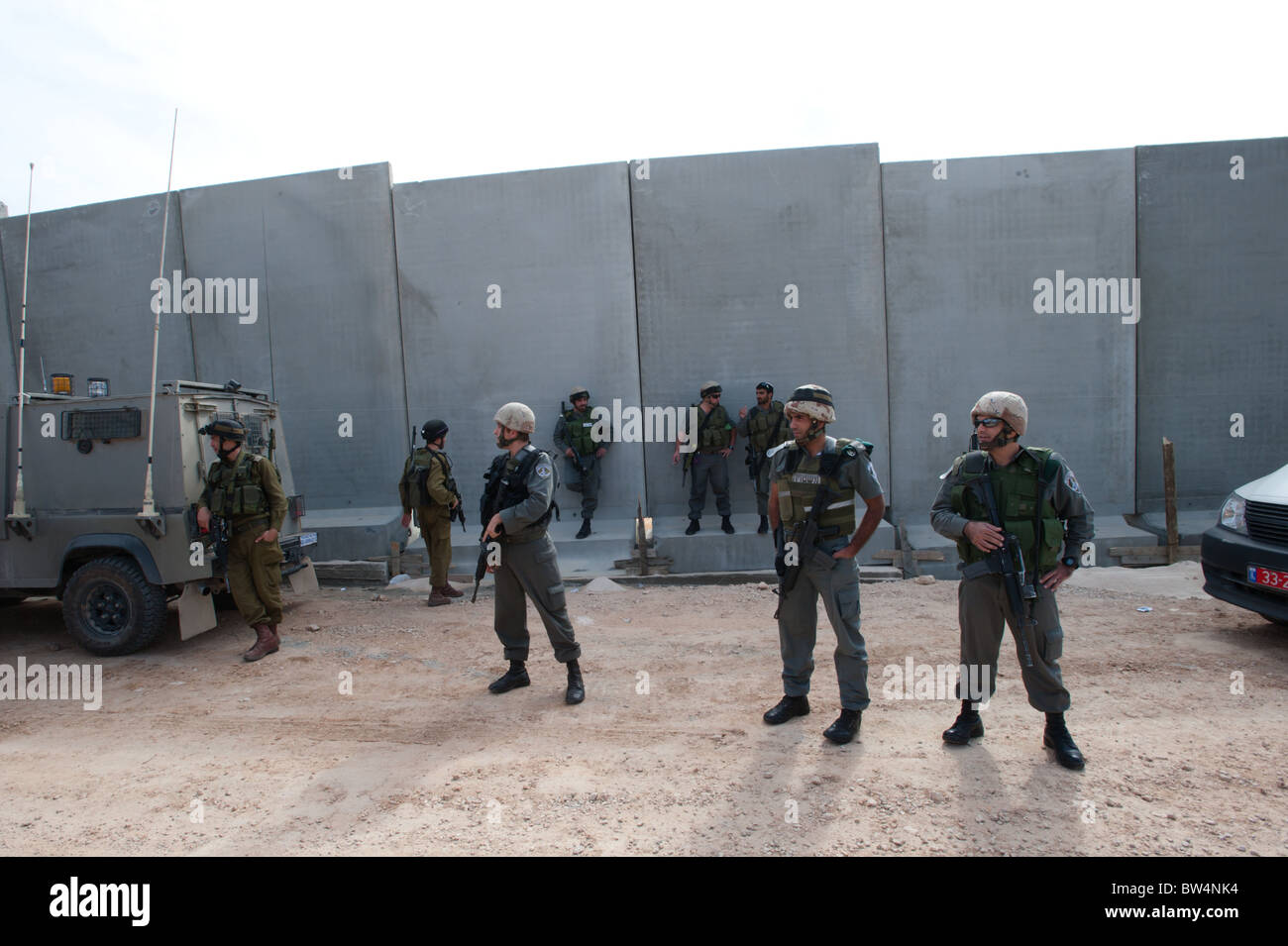 Israeli soldiers stand in front of the Israeli separation barrier which threatens to encircle the West Bank town of Al-Walaja. Stock Photo