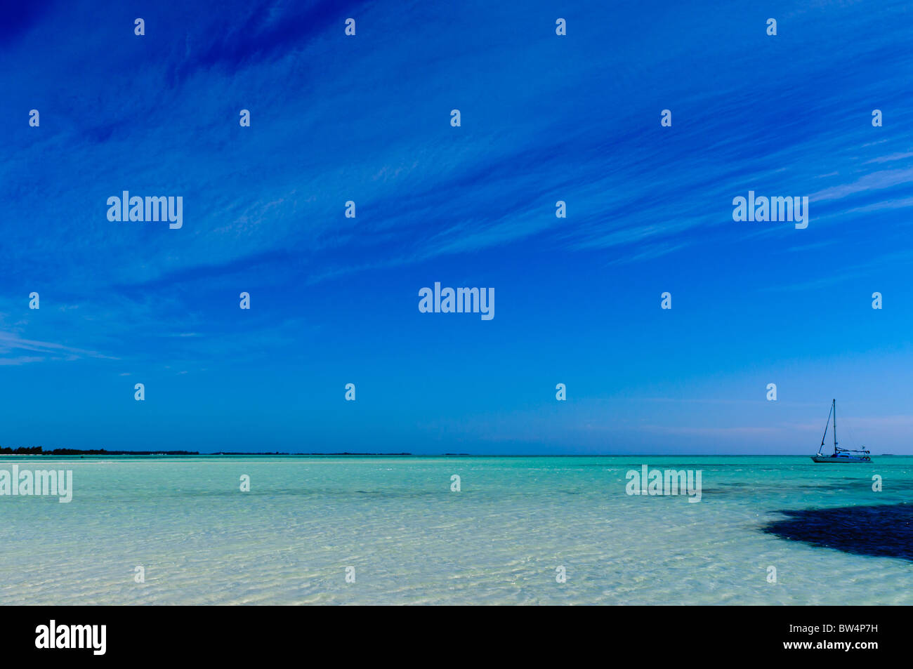 Tropical paradise: turquoise sand beach, yacht ship under blue sky Stock Photo