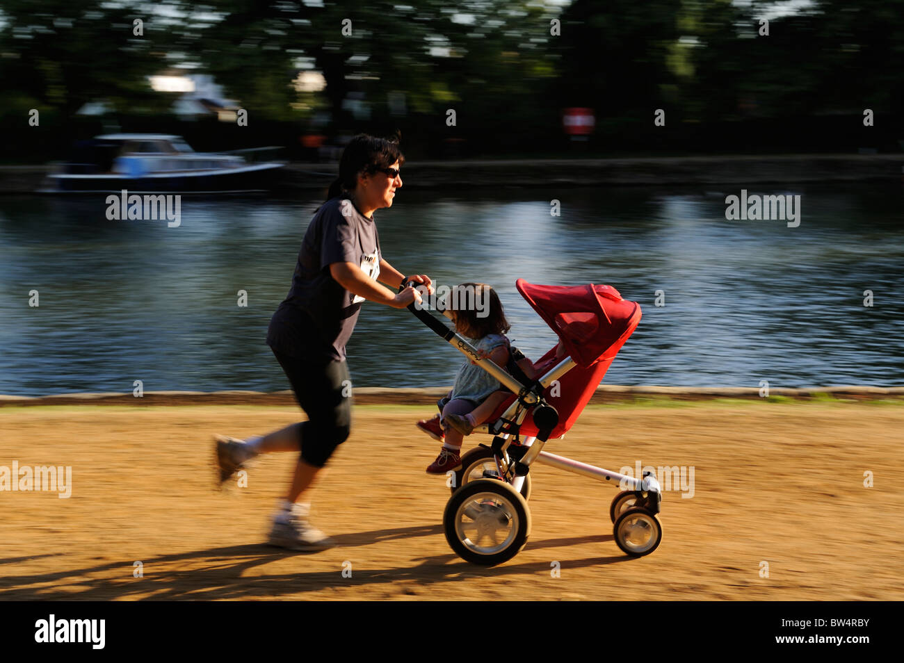 Woman running with pram with kids Stock Photo