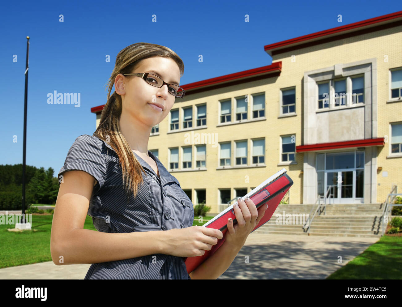 Female student in front of school Stock Photo