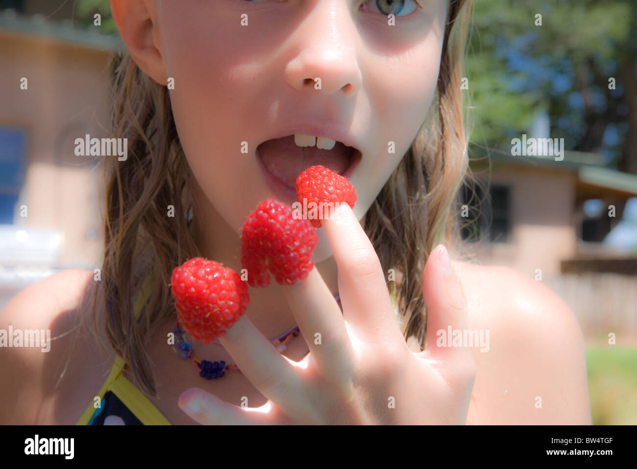 girl with raspberries on her fingertips, mouth open Stock Photo