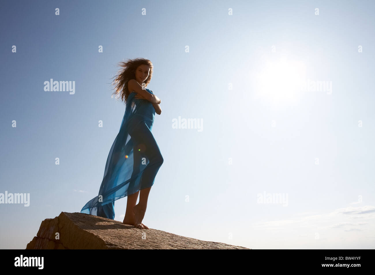 Photo of graceful female folded in dark blue chiffon shawl with sun shining at background Stock Photo