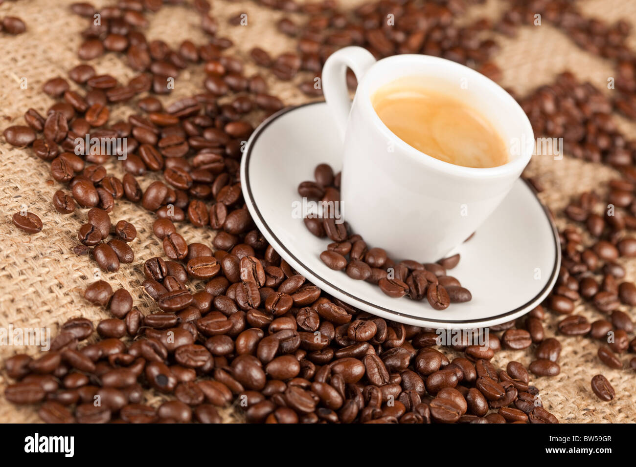 Close-up macro of espresso cup with coffee beans in background. Stock Photo