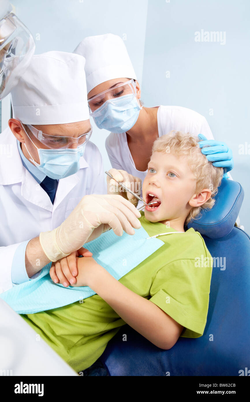 Image of dental checkup given to little boy by dentist with assistant nearby Stock Photo